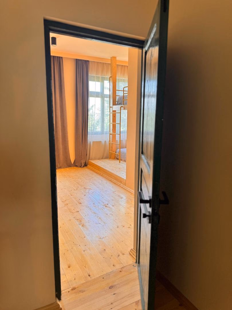 Pale pine floors and long curtains in the Gombori room, with light coming through the window
